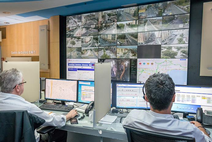 EMT Madrid Salle de contrôle avec deux travailleurs surveillant les routes et les données affichées sur un mur vidéo.