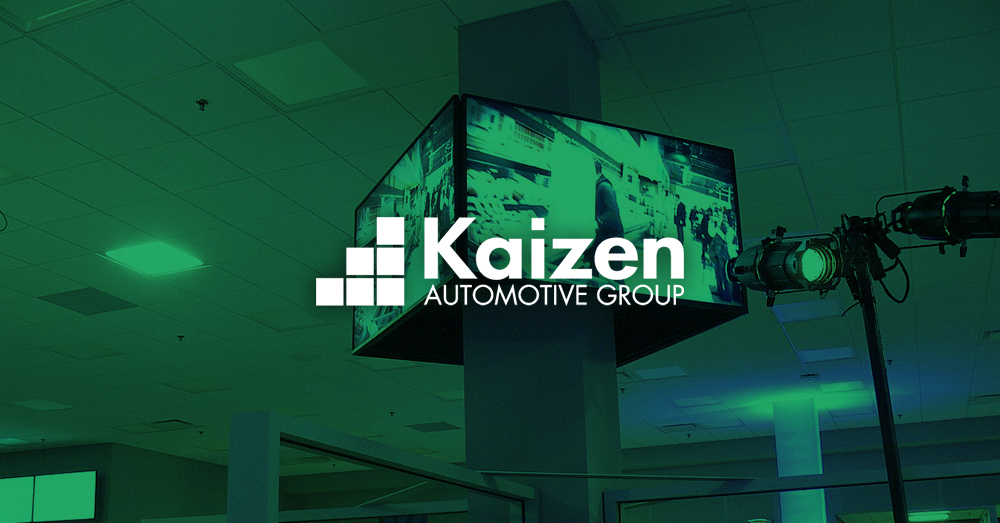 Mur vidéo affichant une publicité pour une voiture dans une concession appartenant au groupe Kaizen Automotive, avec une superposition verte et un logo.