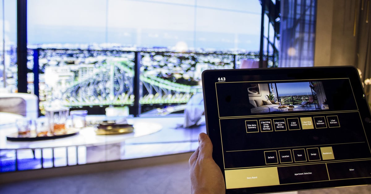 Bureau de vente Q1 Design en Australie, avec un mur vidéo présentant des photos de propriétés, sélectionnées sur une interface tablette
