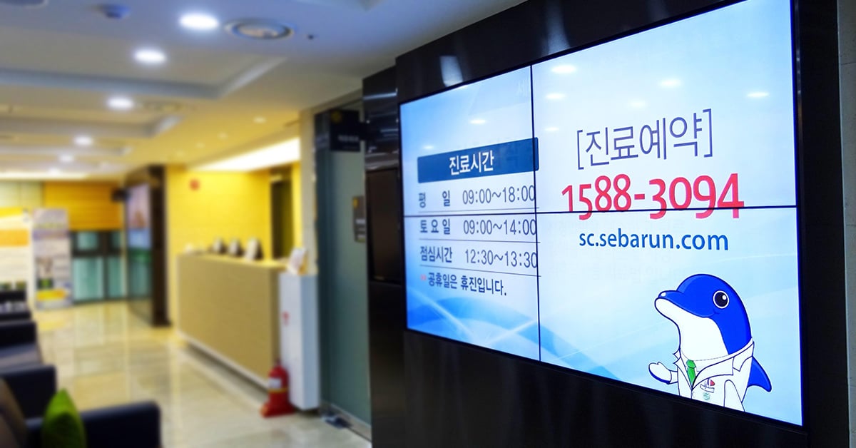 Salle d'attente de l'hôpital Seocho Se Barun, avec un mur vidéo affichant les horaires et les coordonnées des personnes à contacter