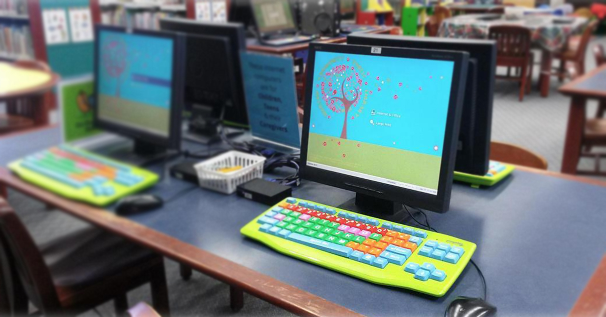 Une table dans la bibliothèque publique de la Communauté de Varsovie avec des ordinateurs utilisant Userful Desktop et des claviers colorés.