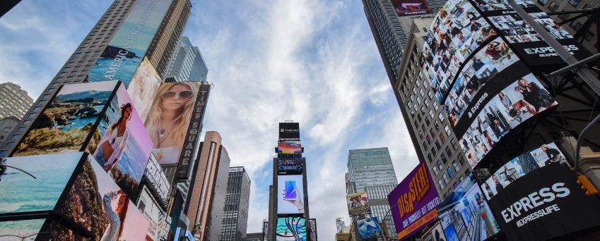 Le Times Square de New York est rempli de murs vidéo et de panneaux numériques, et de nombreuses personnes en journée.