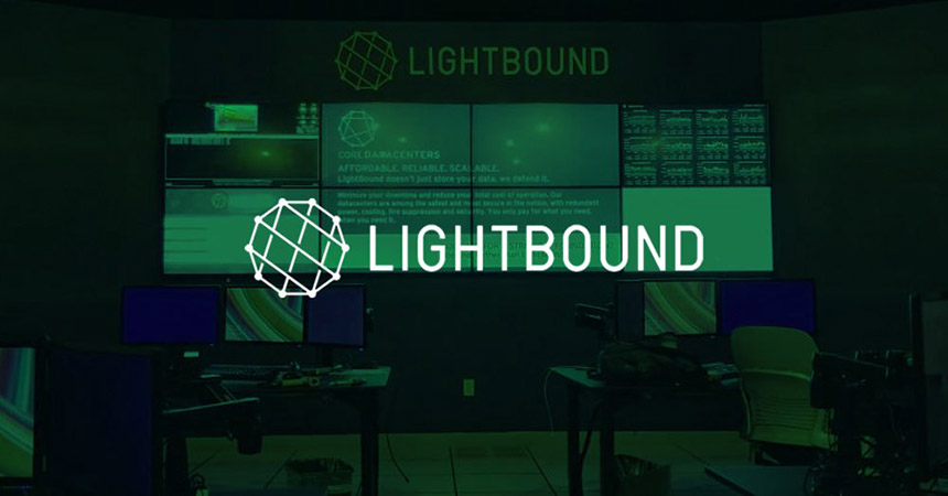 Salle de contrôle vide de Lightbound avec 2 postes de travail et un mur vidéo affichant des sites web, des données et des publicités avec une superposition verte et un logo.