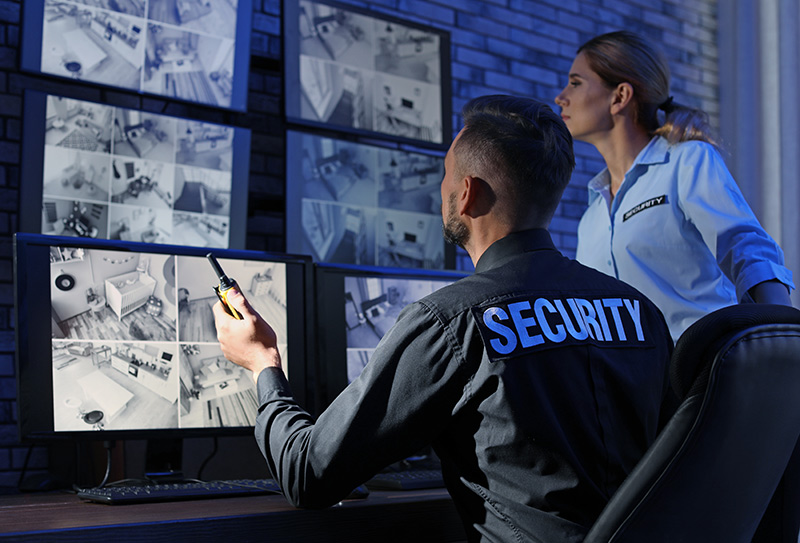 2 agents de sécurité surveillent l'intérieur d'un bâtiment grâce à des images en direct sur un mur vidéo.