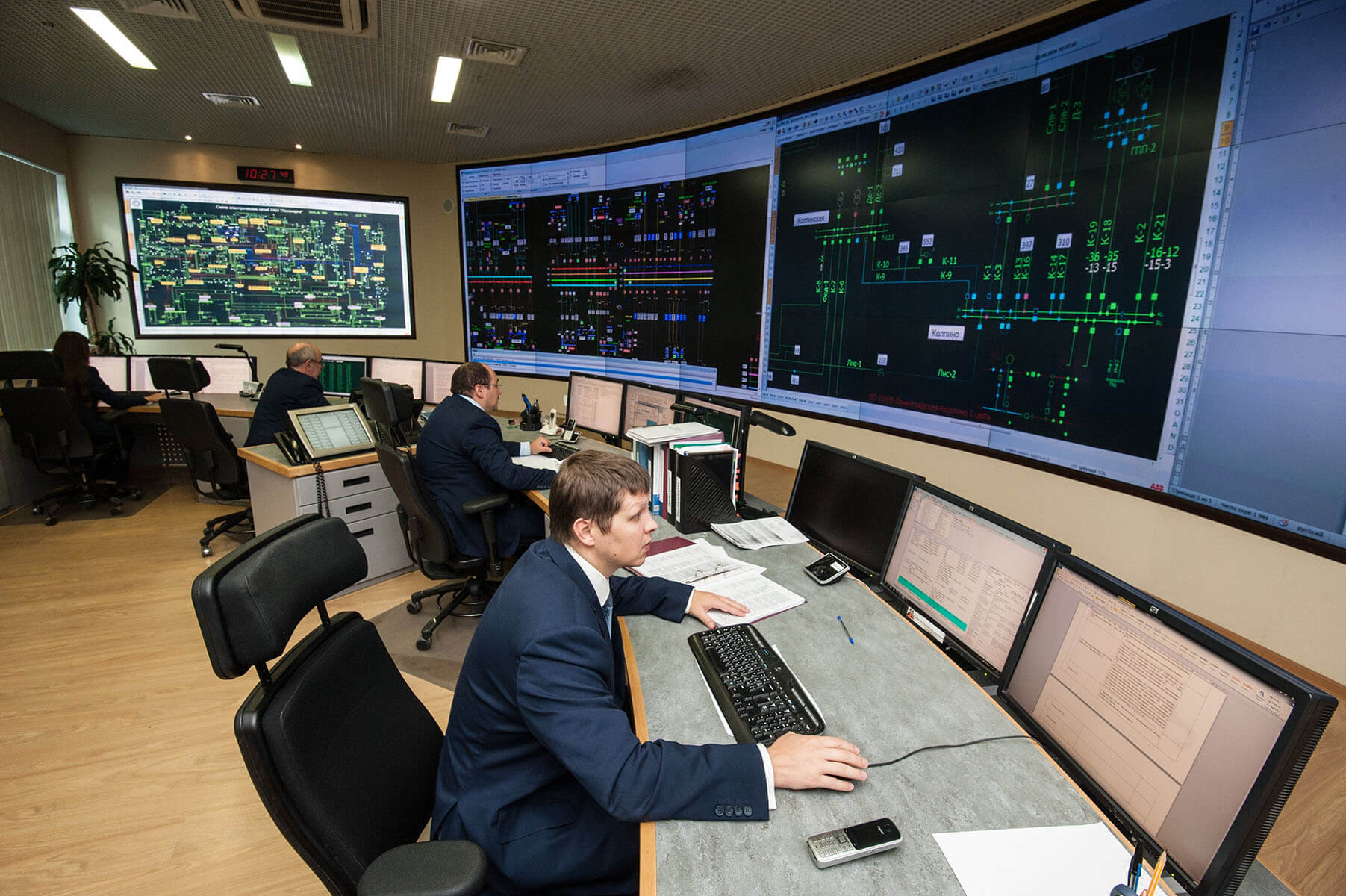 Employés travaillant dans une salle de contrôle sur des postes de travail avec des murs vidéo affichant des données sur l'infrastructure informatique.